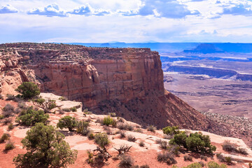 A rocky cliff overlooks a desert landscape