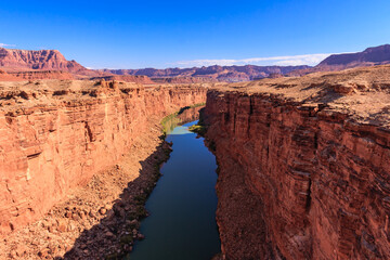A river runs through a canyon with a clear blue sky above