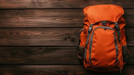 An orange backpack rests on a wooden surface, showcasing its durable design perfect for outdoor activities, This image can be used for travel, adventure blogs, or marketing outdoor gear,
