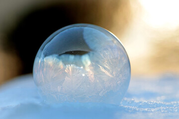 A frozen bubble in the snow. Beautiful frosty patterns on a frozen soap bubble. winter, frosty background. Frozen bubble. soap bubble on snow close up. winter season, cold time. macro photo