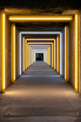 Fototapeta premium A long hallway with yellow lights in a concrete building