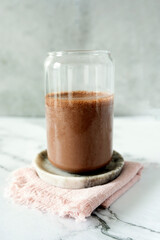 A chocolate protein shake served in a glass, paired with a bowl of cocoa powder, nutrition.