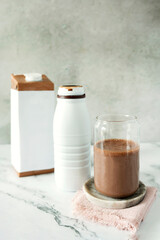 A glass of chocolate protein drink or cocoa complemented by a milk carton.