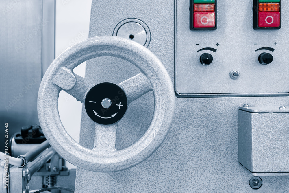 Poster a silver machine with a silver wheel and a red button. the wheel is black and has a smiley face on i