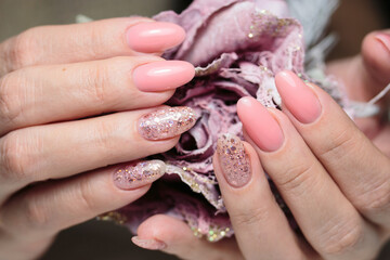 Women's nails with a beautiful pink manicure with glitter. Nail design. Manicure with gel polish close-up