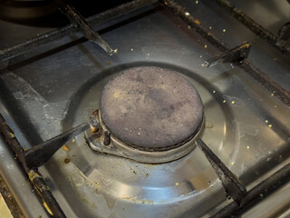 A gas burner with a dirty metal surface, ready for use.