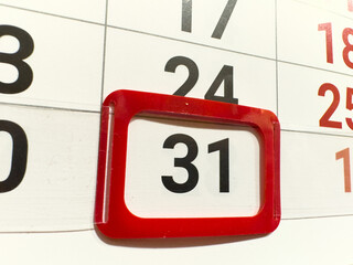 Close-up of a calendar with the date 31 highlighted in a red frame. This is the last day of the month, surrounded by other numbers like 30, 24, and 25