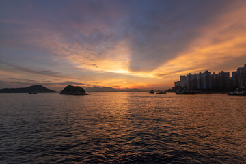 Sunset over the South China Sea, Hong Kong.  Golden hour light illuminates the ocean with calm waves.  Sky filled with vibrant orange and yellow hues.