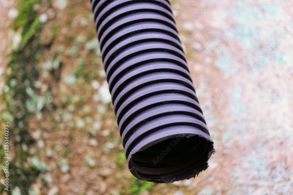 Poster a close-up view of a hose lying on a concrete surface, with details visible.