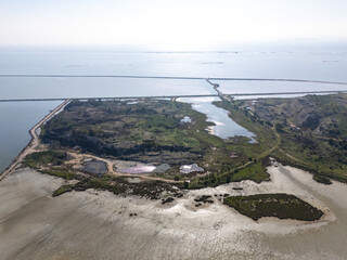 Narrow road dividing calm sea water and salt evaporation ponds in Izmir