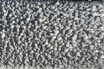 ice layer formed on car door at winter freezing rain on the road, full-frame background and texture