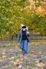 Girl walking through an autumn park with a guitar on her shoulder