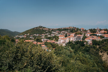 Panoramic view of Sighnaghi, Georgia, a historic town with red rooftops and lush green hills, overlooking the Alazani Valley on a clear summer day