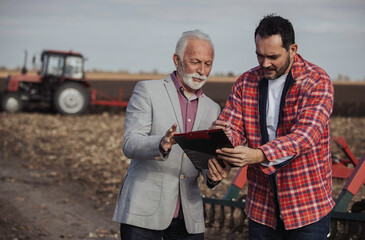 Businessman and farmer signing documents in field