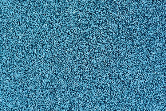 A close-up shot of a blue rubber playground surface
