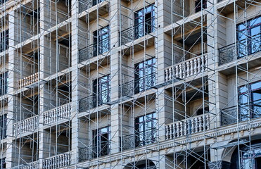 Facade of a multi-story building under construction with scaffolding and balconies.
