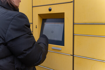 A woman stands in front of a packing station in Germany and takes a package out of a compartment