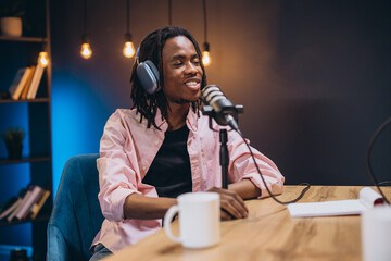 Radio host speaking into microphone, recording podcast in home studio, broadcasting professional...