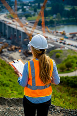 Obraz premium A woman in a hard hat and safety vest holding a clipboard