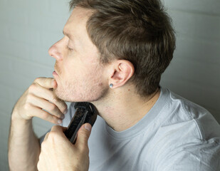 man trims his beard with a trimmer. Close up. An electric razor trimming a beard. Beard care at home.