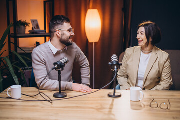 Professional podcasters speaking into microphones, collaborating and smiling during recording...
