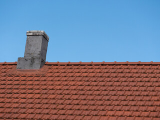 roten Dach mir Schornstein vor blauem Himmel