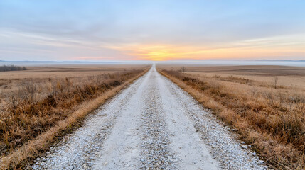 Naklejka premium Sunrise over flat farmland, gravel road vanishing point