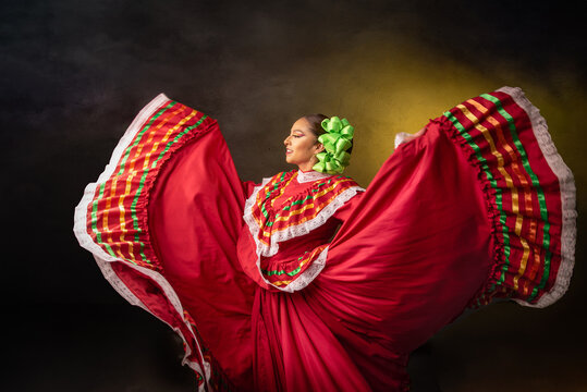 A woman in a red dress is dancing with a green flower in her hair