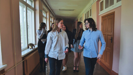 High school students enjoying their break time, walking and chatting in the school hallway