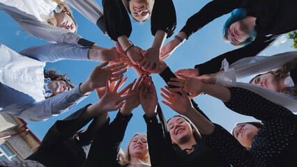 Group of students joining hands together in a circle, celebrating their school day with unity and enthusiasm