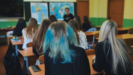 Students are attentively listening to their geography teacher during a lesson in the classroom