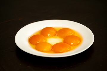 egg yolks on white plate isolated on black background