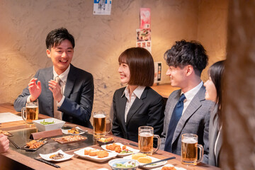居酒屋で新入社員の歓迎会をするビジネスパーソン