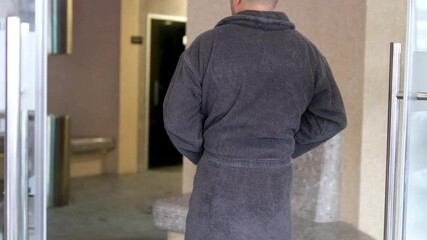 hamam man 48 year old Brazilian man wearing a robe and drinking a cup of tea and smiling at the camera.