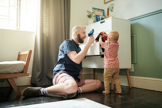 Getting ready, kids and a father helping his son to pick an outfit from the cupboard in a bedroom. Children, clothes and dressing with a young man teaching his toddler child about chores or packing