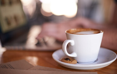 Coffee, person and relax in restaurant for hospitality, service and laptop for remote work. Mug, customer and latte at cafe table for drink, caffeine and cappuccino at bokeh with tech for networking
