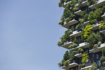 Residential tower, an example of modern architecture with various plants and tree-covered balconies. Sustainability and tree skyscraper concept.