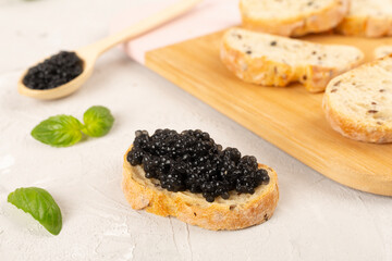 Bread slice with black caviar served on on wooden table