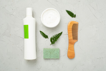 Shampoo and hair mask with green leaves on concrete background, top view