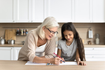 Happy senior grandmother and preteen age kid granddaughter spend leisure time together enjoy...