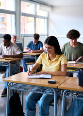 Vertical. Diverse group of multiracial students aged 18 to 20 in a classroom, attentively taking notes during a lecture. The scene reflects unity, education, and the pursuit of knowledge