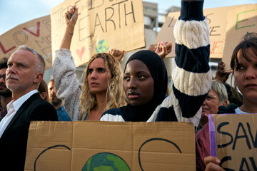Serious Muslim woman holding a banner in a protest by a group of people at a demonstration on...