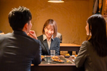 先輩社員と居酒屋で話をするフレッシュな女性