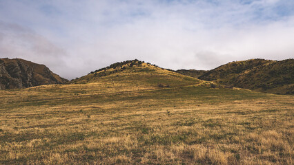 Yellow brown hills of alexandra central otago low dramatic clouds heavy sky hiking tramping 