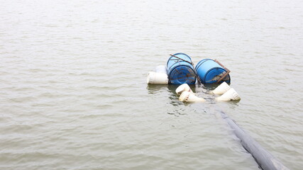 Buoy for water pumping. Blue and white tank supporting the water pumping pipe in the pond of water supply or agriculture pumping station on water surface background with selective focus.