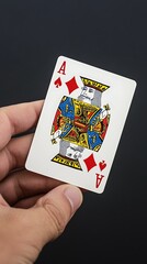 A hand holding an Ace of Spades playing card against a dark background.