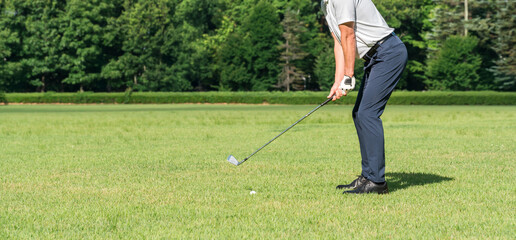 ゴルフ場でゴルフをするゴルファーの男性の足元（アイアンショット）
