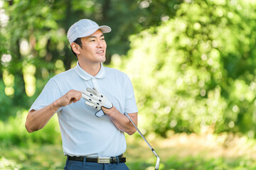 新緑の中でゴルフウェアを着た男性ゴルファー
