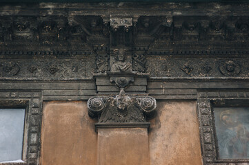 A baroque brown capital and a relief order showing seraphims and plant elements in close-up. The ancient architecture of the Boim Chapel in Lviv, Ukraine.