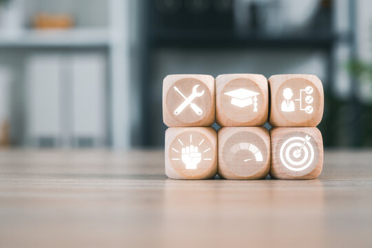 Wooden blocks with icons symbolizing apprenticeship, showcasing tools, education, and goals on a wooden surface.